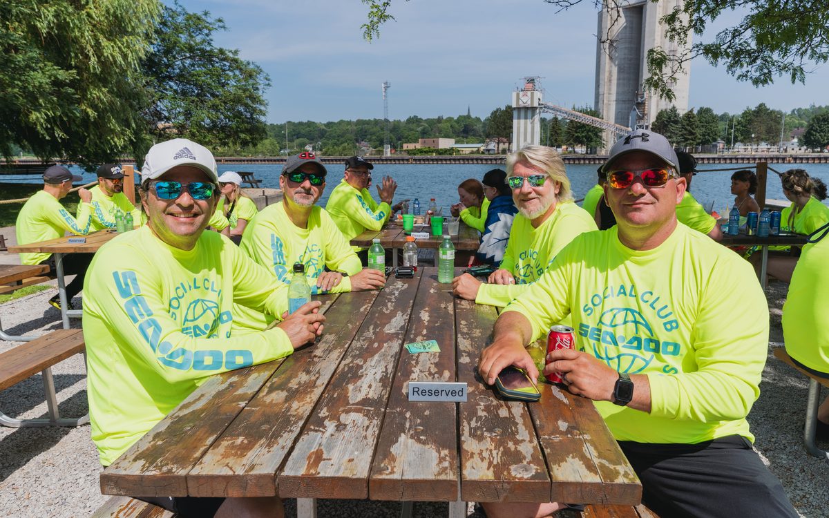 Riders in matching high-visibility jerseys at a picnic table between legs of a group ride